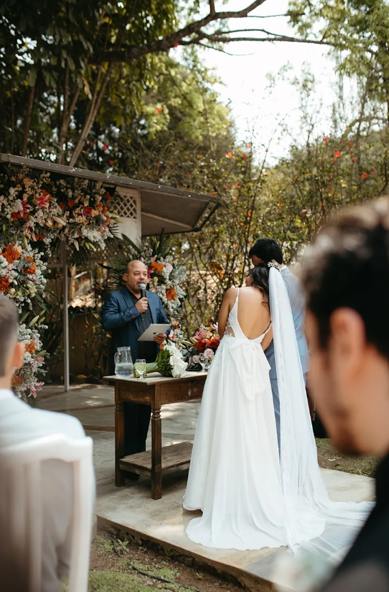 Celebrante conduzindo a cerimônia dos noivos diante do altar de flores no jardim